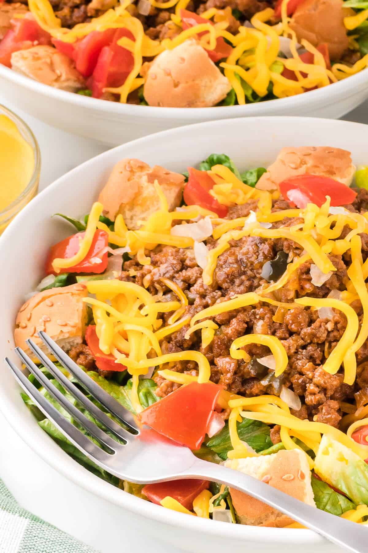 A bowl of cheeseburger salad with a fork.