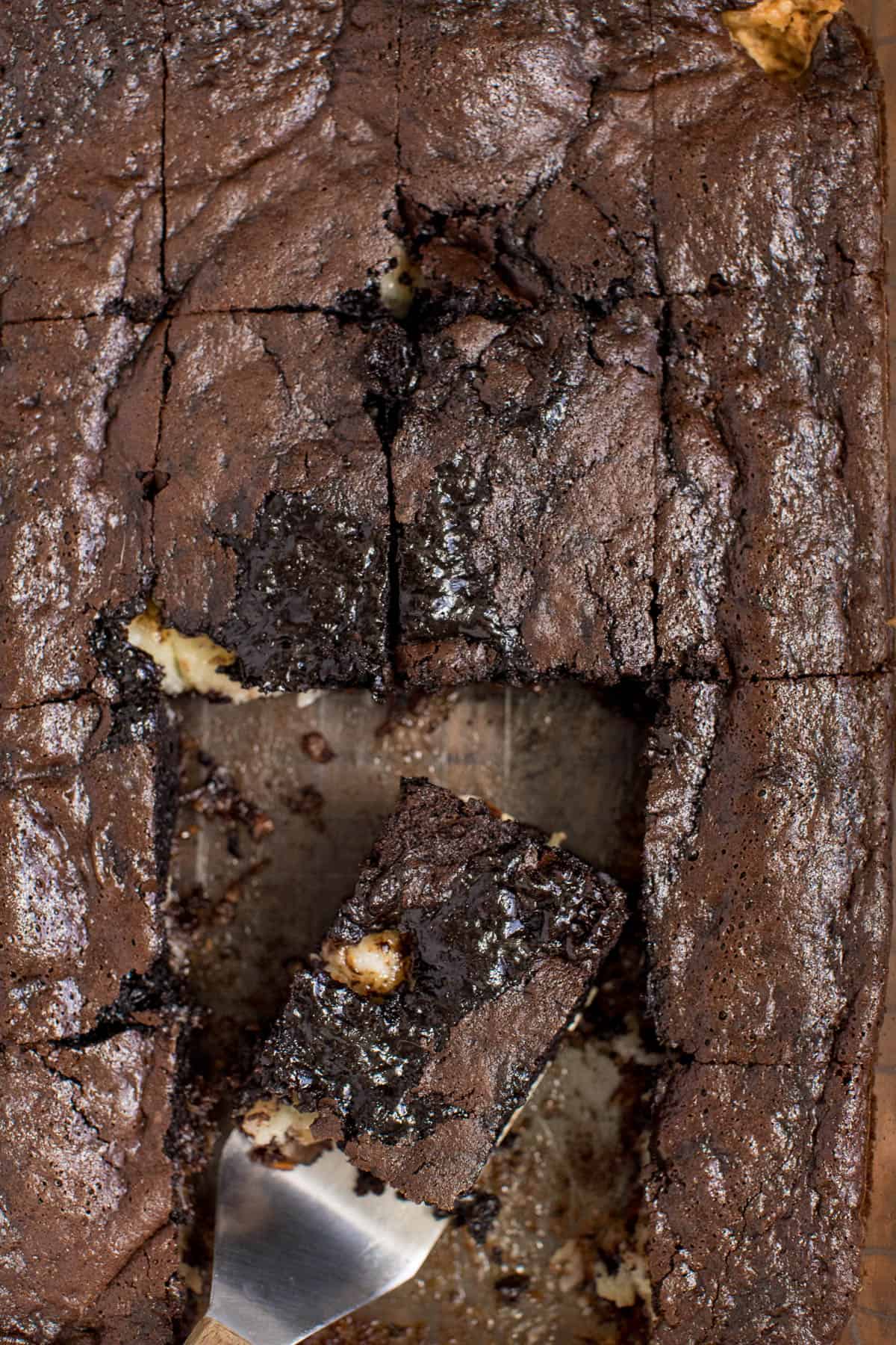 A pan with earthquake cake with pieces cut and one piece on a spatula.