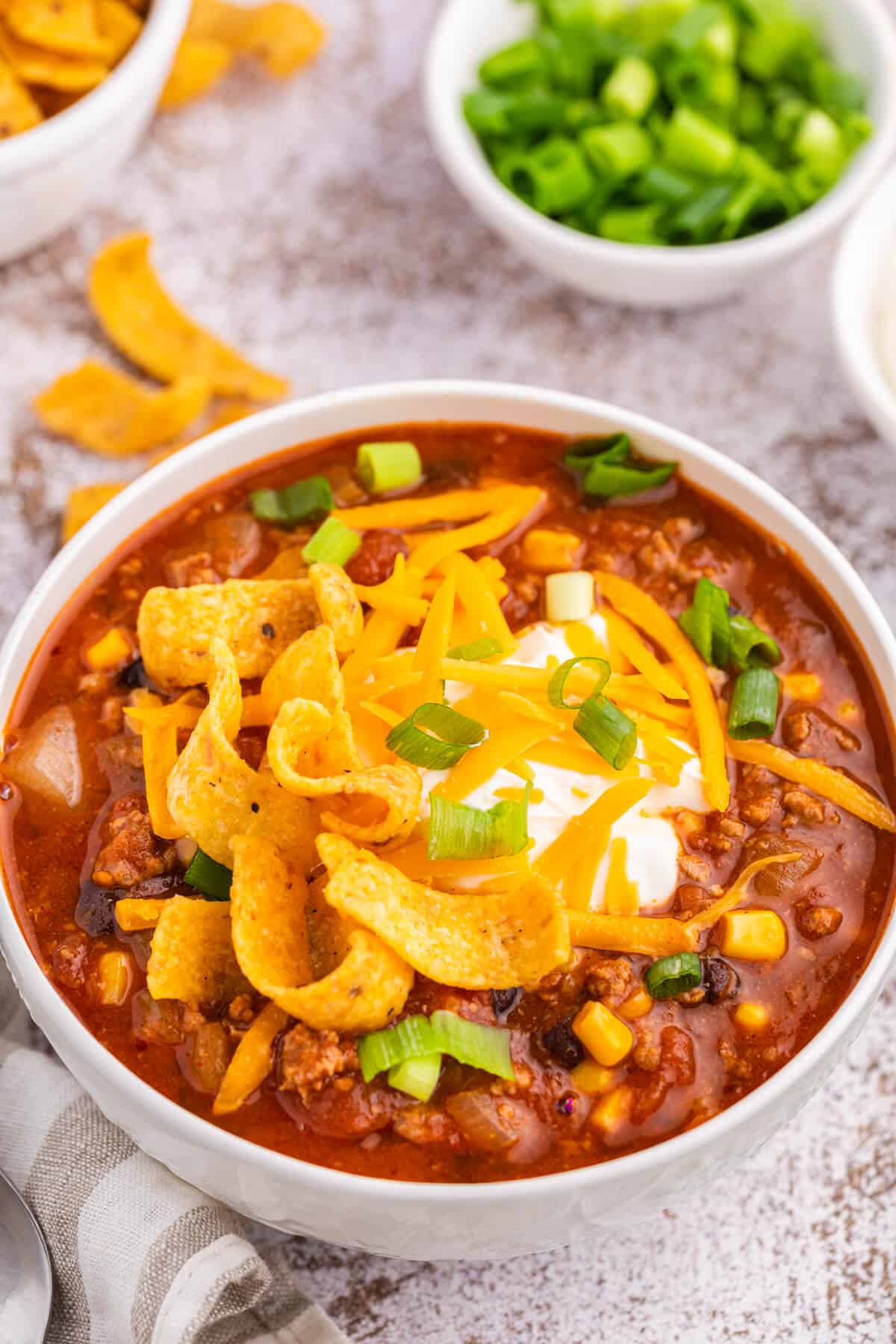 Taco chili in a white bowl with toppings.