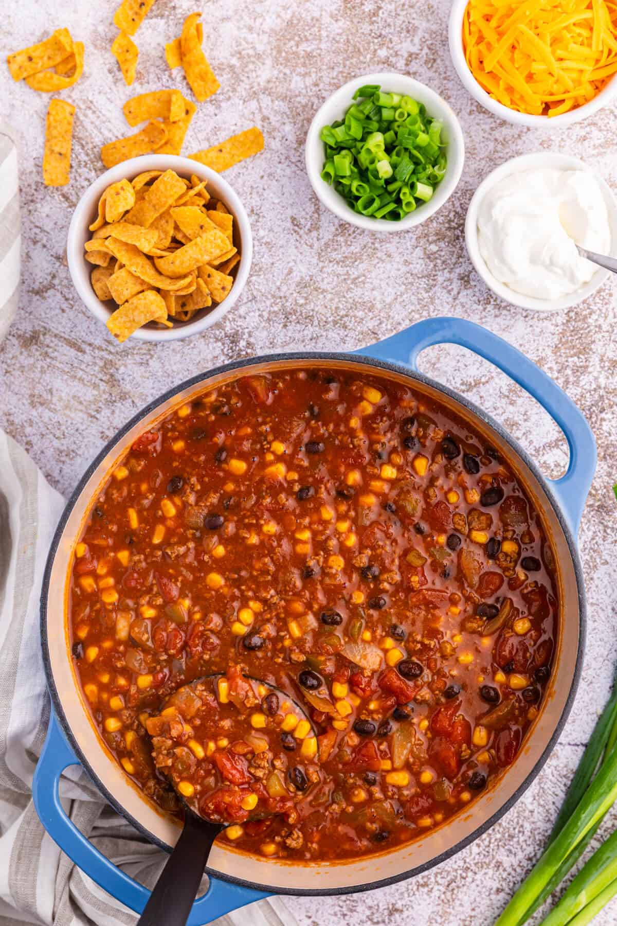 Taco chili in a dutch oven with a black ladle.