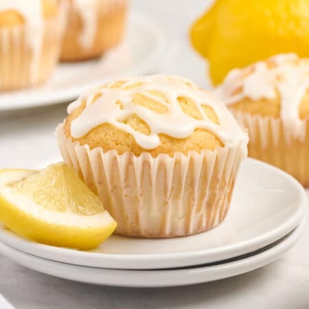 A lemon pound cake muffin on a stack of two plates with a lemon slice.