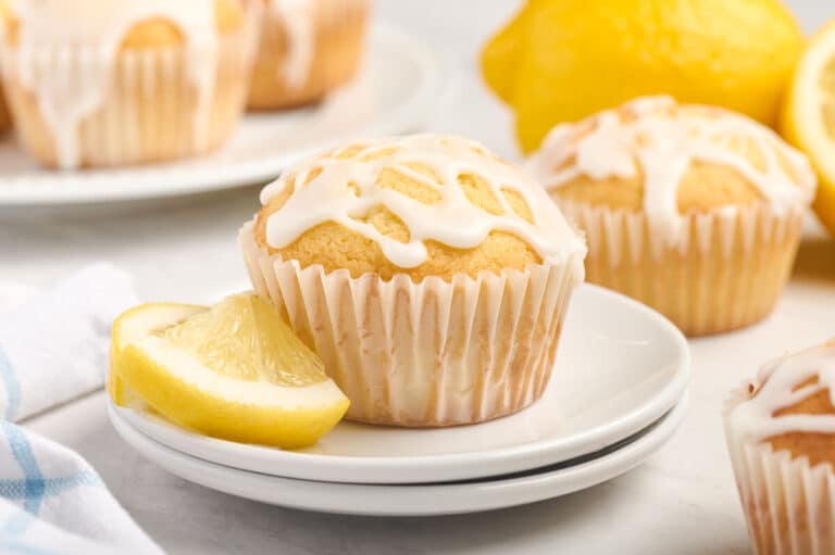 A lemon pound cake muffin on a stack of two plates with a lemon slice.