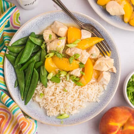 Peach chicken on plate with rice and snow peas.