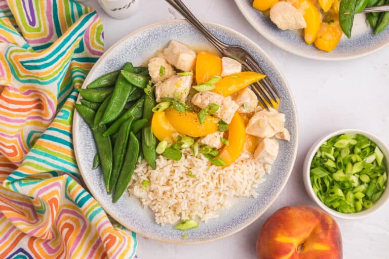 Peach chicken on plate with rice and snow peas.