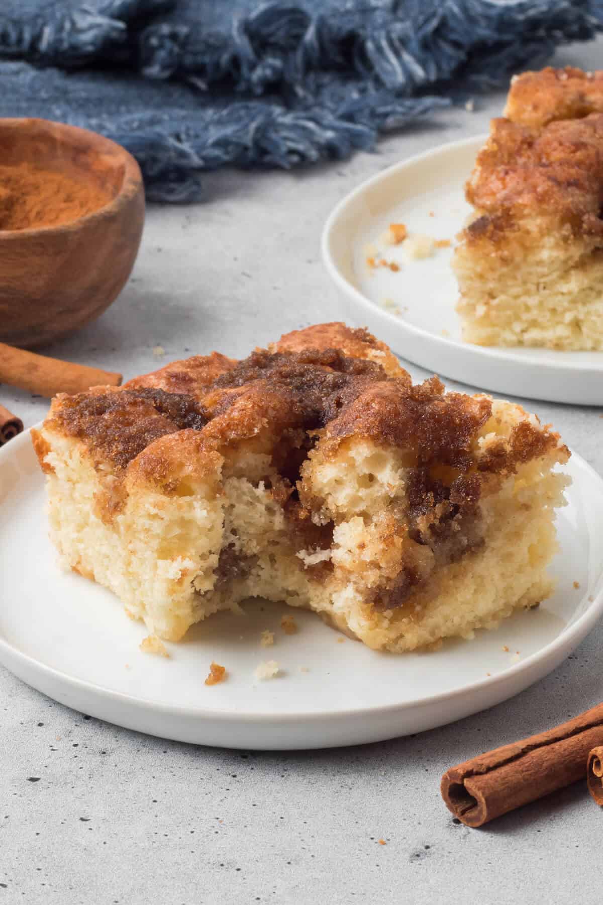 Cinnamon coffee cake on a plate with a bite out of it.