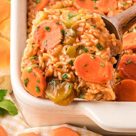 The recipe in a pan and a wooden spoon serving a scoop of it.