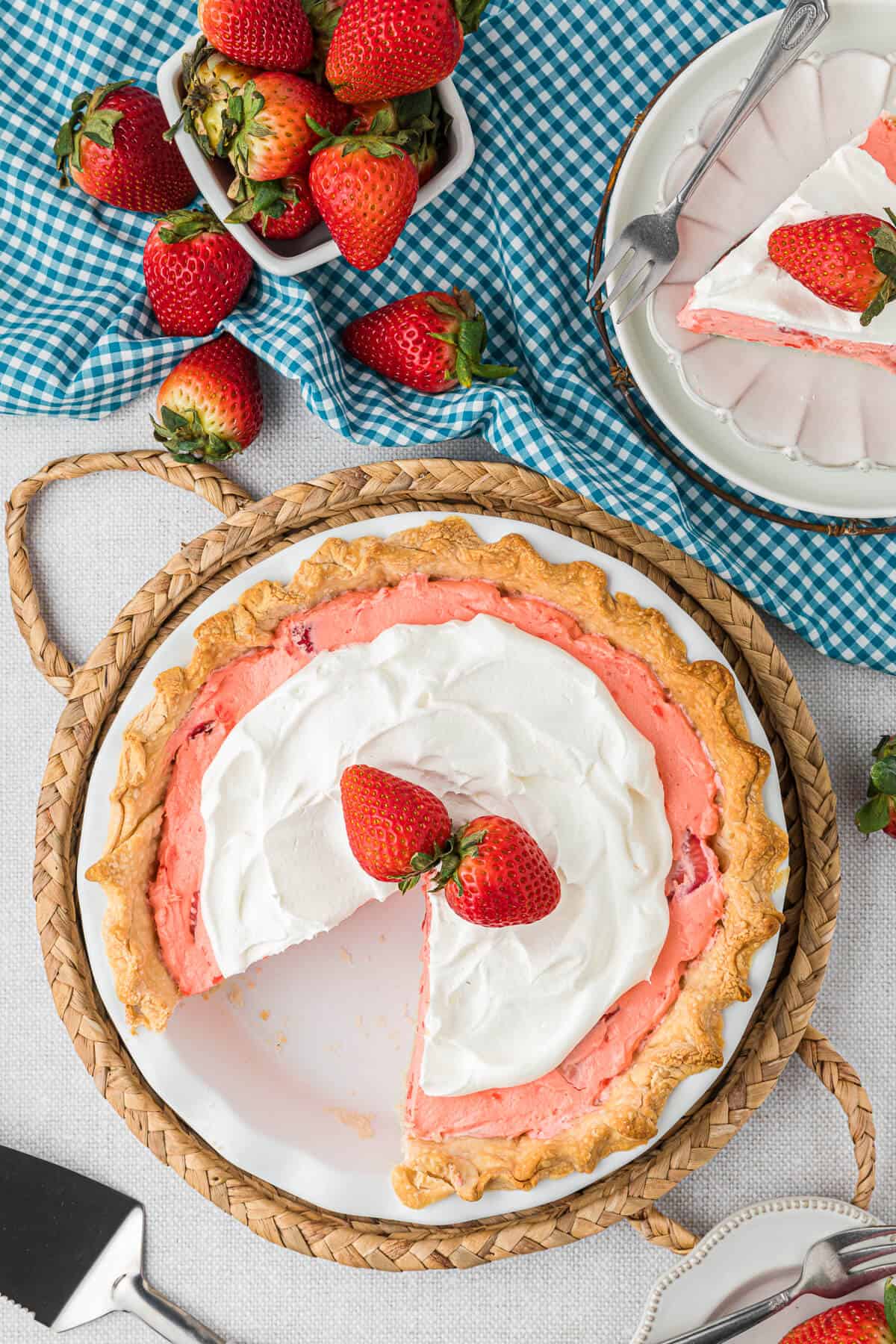 A strawberry cream pie with a slice out of it.