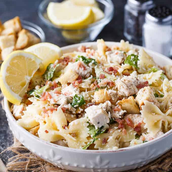 Chicken Caesar Pasta Salad - The BBQ side you'll make every summer! Take your favorite salad poolside with this spin on bowtie pasta salad with homemade caesar dressing and crispy bacon.