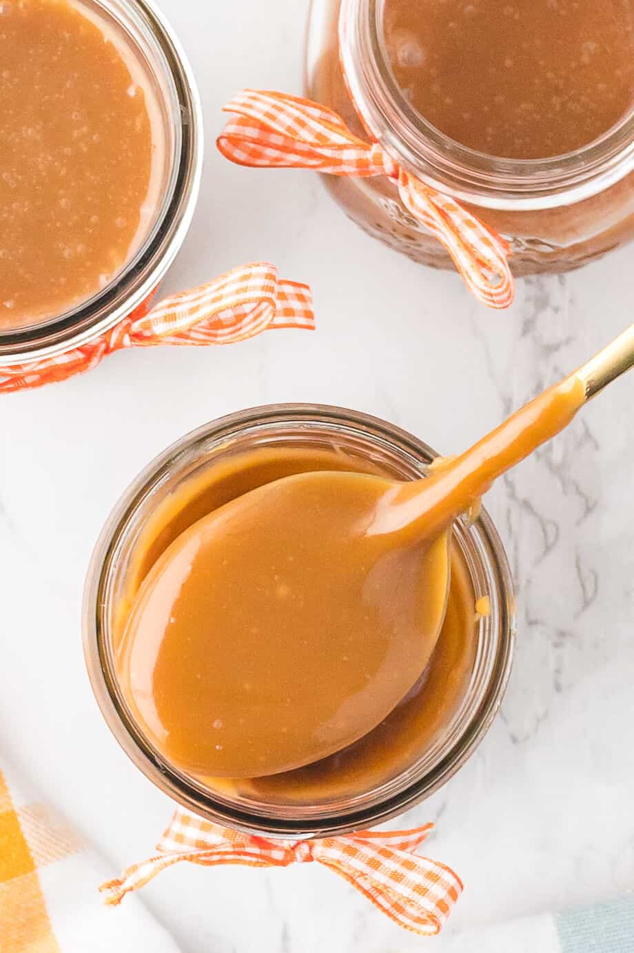 A spoon of butterscotch sauce over a jar.