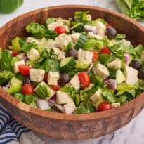 The salad in a wooden bowl on a white counter.