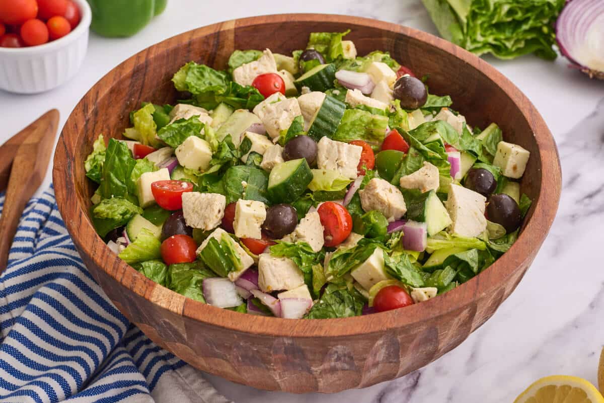 The salad in a wooden bowl on a white counter.