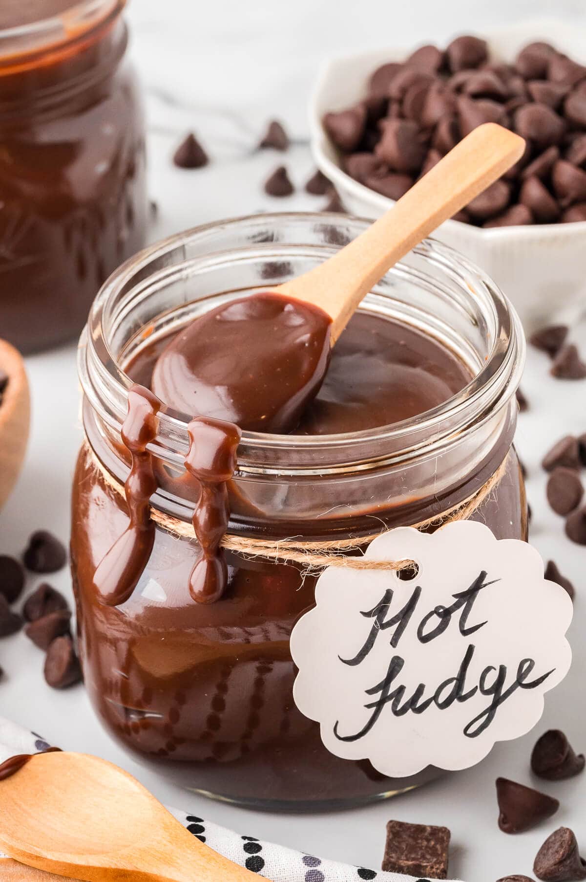 A jar of hot fudge sauce with a wooden spoon.