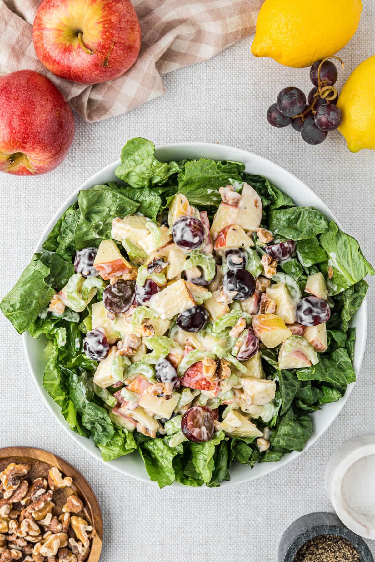 A bowl of Waldorf salad surrounded by ingredients.