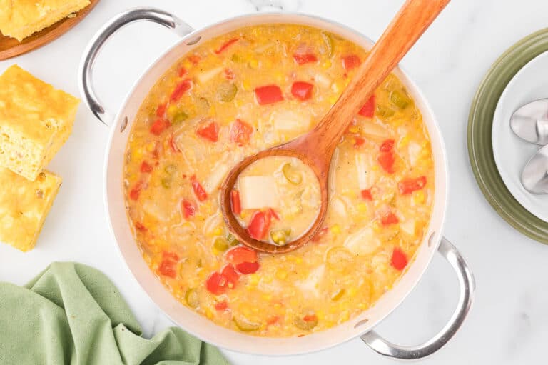 Corn chowder in a pot with a wooden ladle.