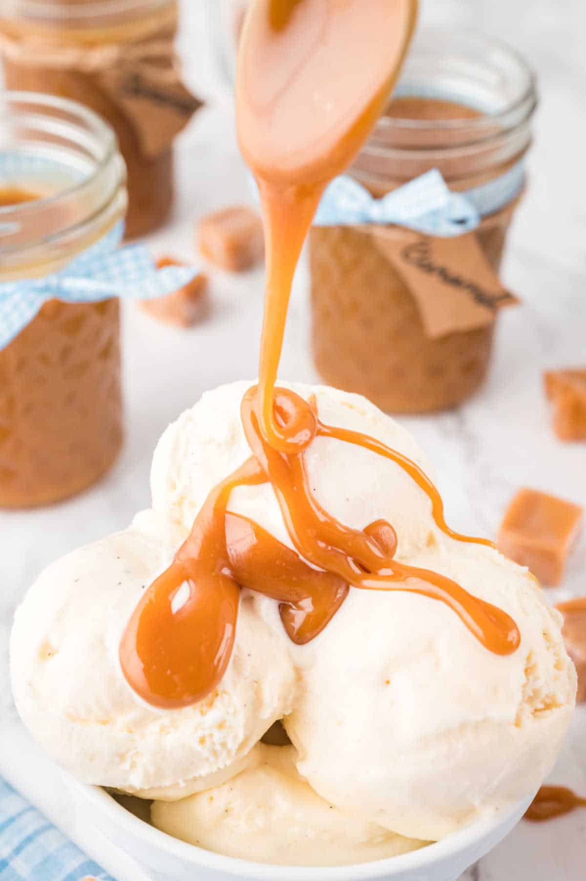 Caramel sauce being poured on a bowl of vanilla ice cream.