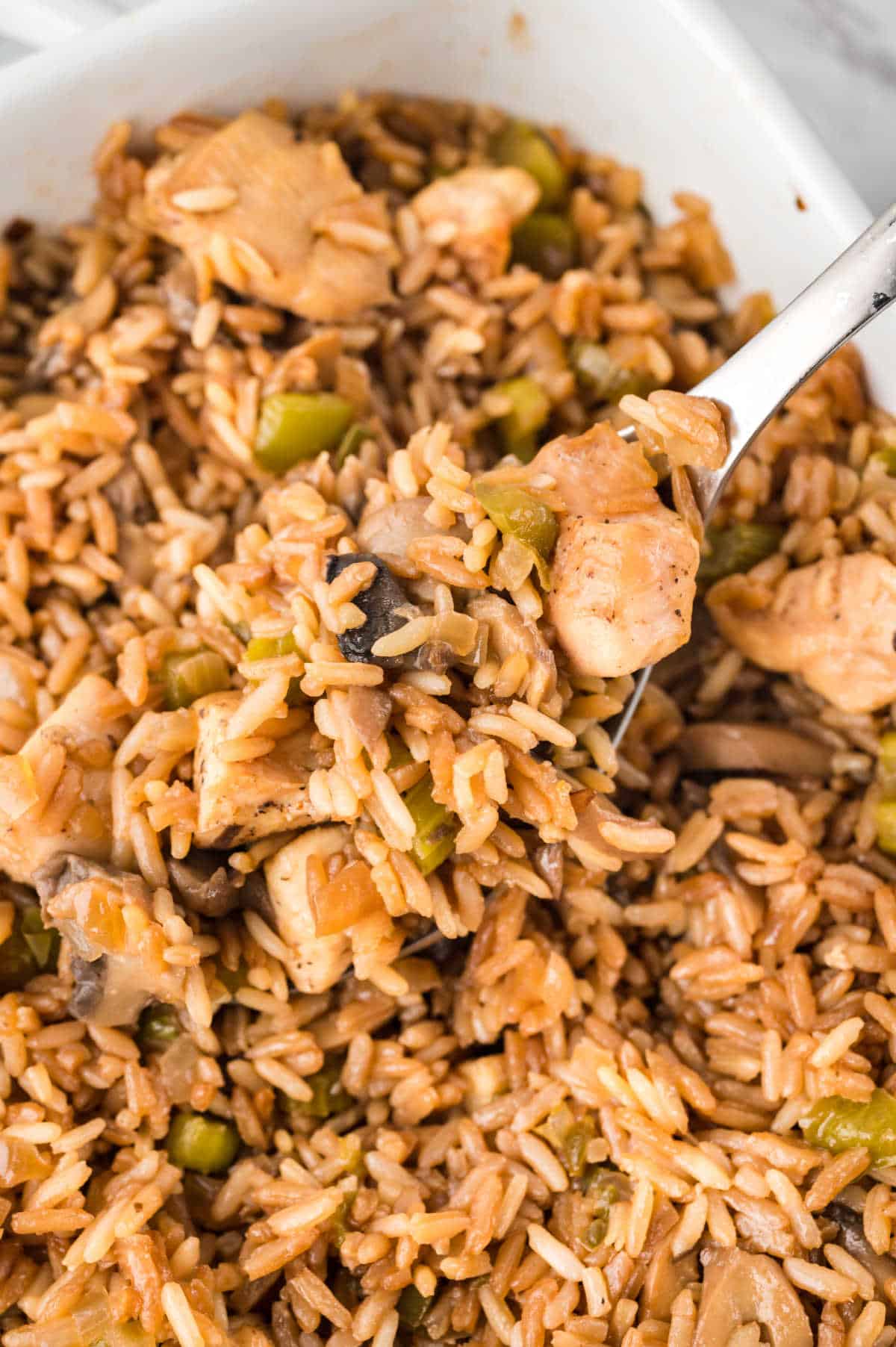 Chicken fried rice in a casserole dish with a serving spoon.