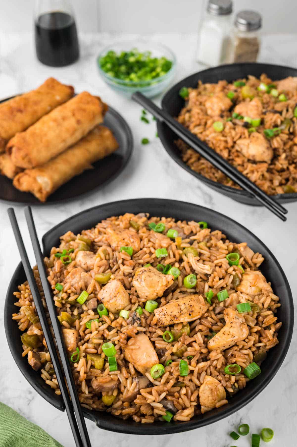 Chicken fried rice in a black bowl with chopsticks.