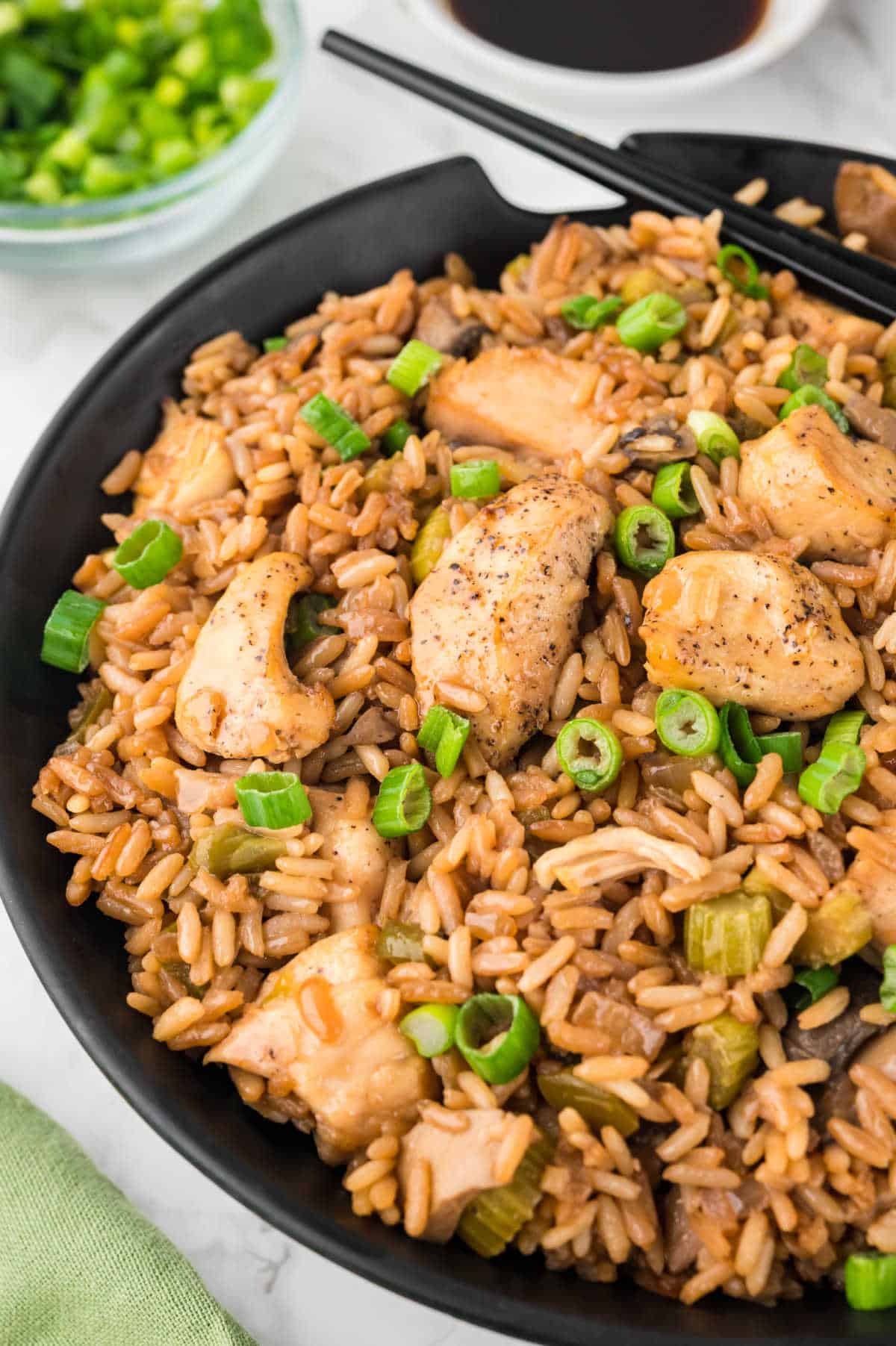 A black bowl of chicken fried rice.