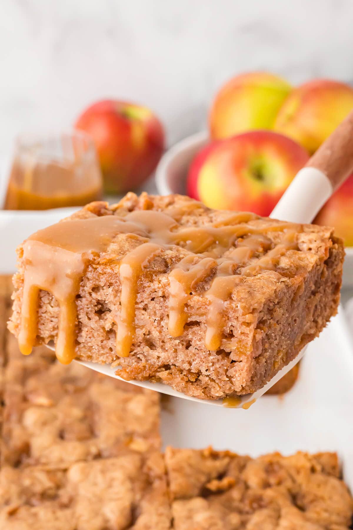 A slice of apple cake with butterscotch sauce on a serving spatula.