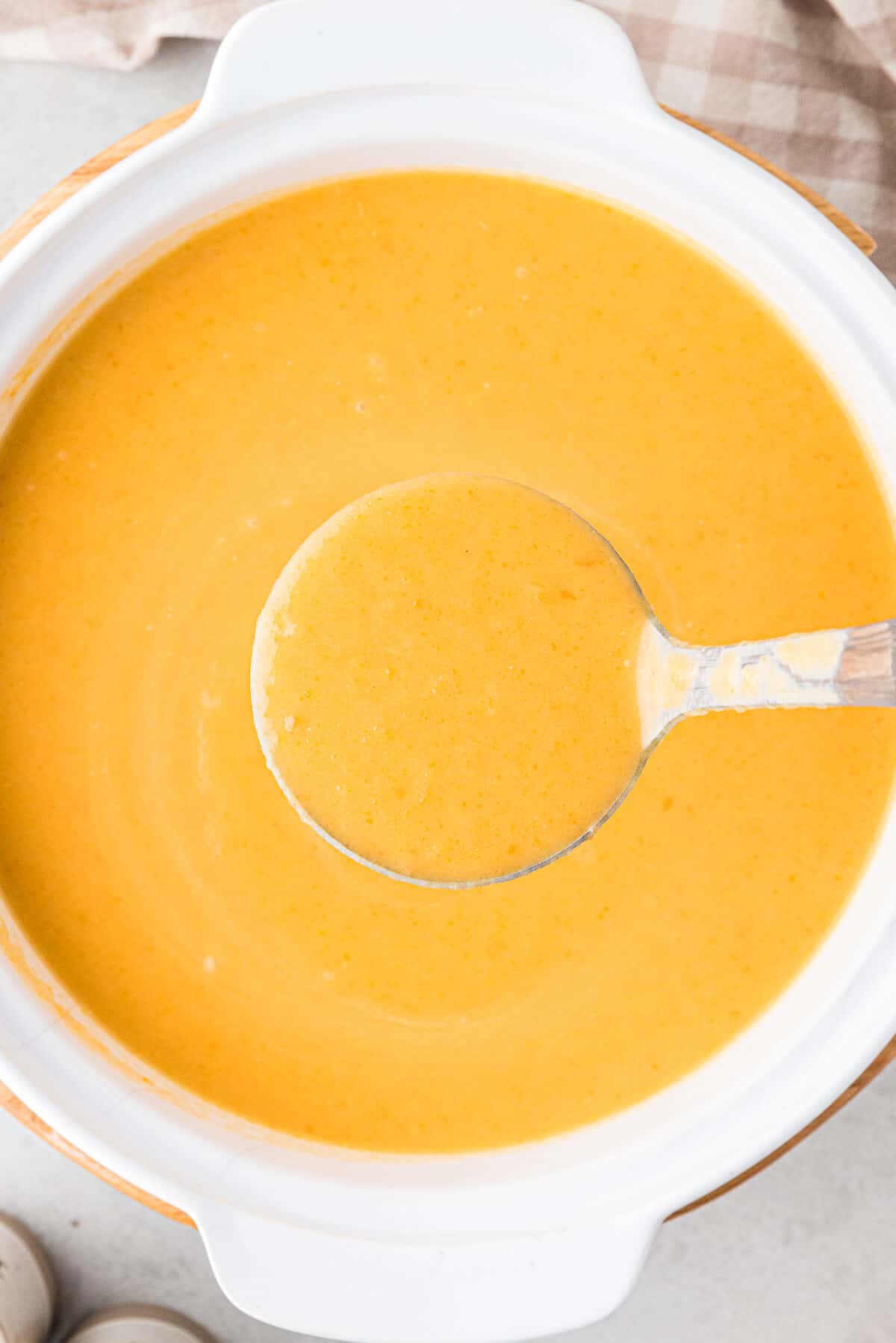 A pot of cream of carrot soup with a ladle.