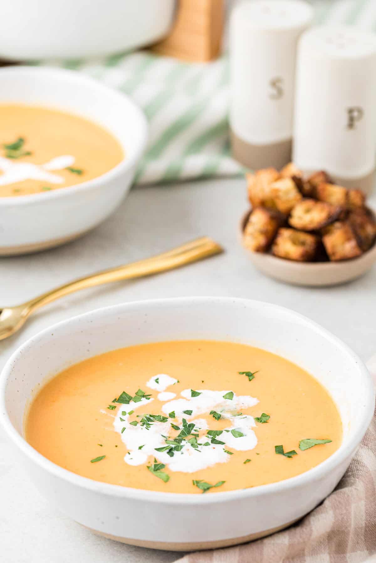 A white bowl of cream of carrot soup.