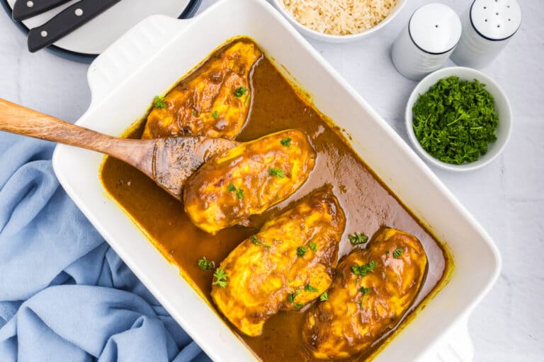 Honey curried chicken in a pan with a serving spoon.