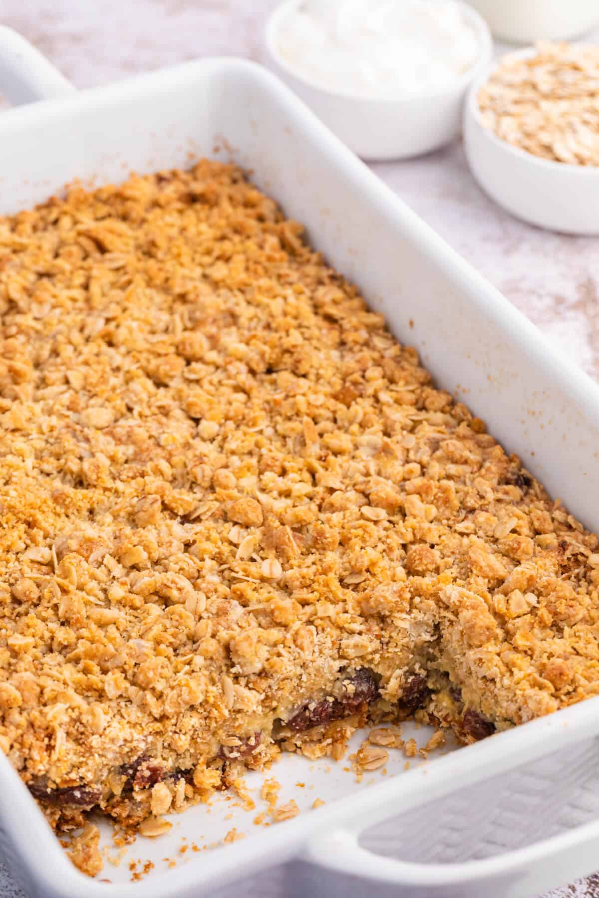 Sour cream raisin bars in a pan with a few squares cut out.