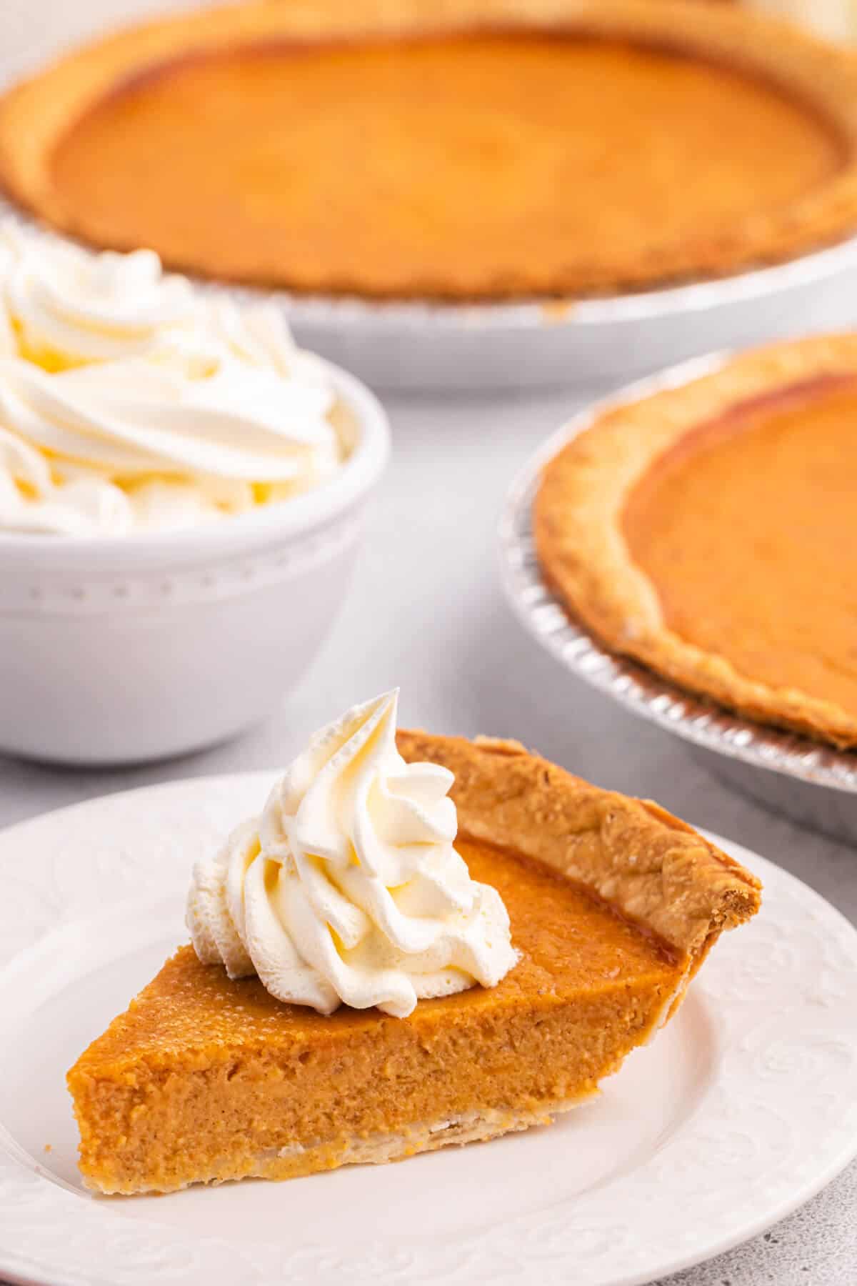 Sweet potato pie slice with whipped cream on a plate.