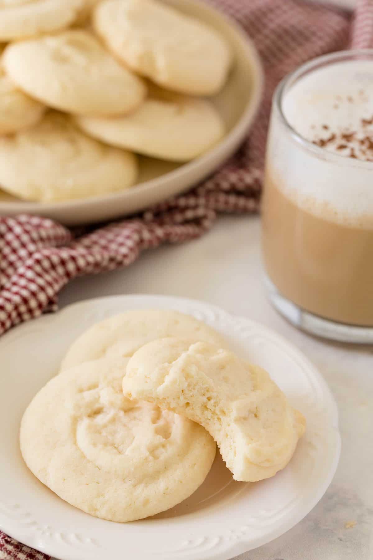 Whipped shortbread cookies on a plate with a bite out of one cookie