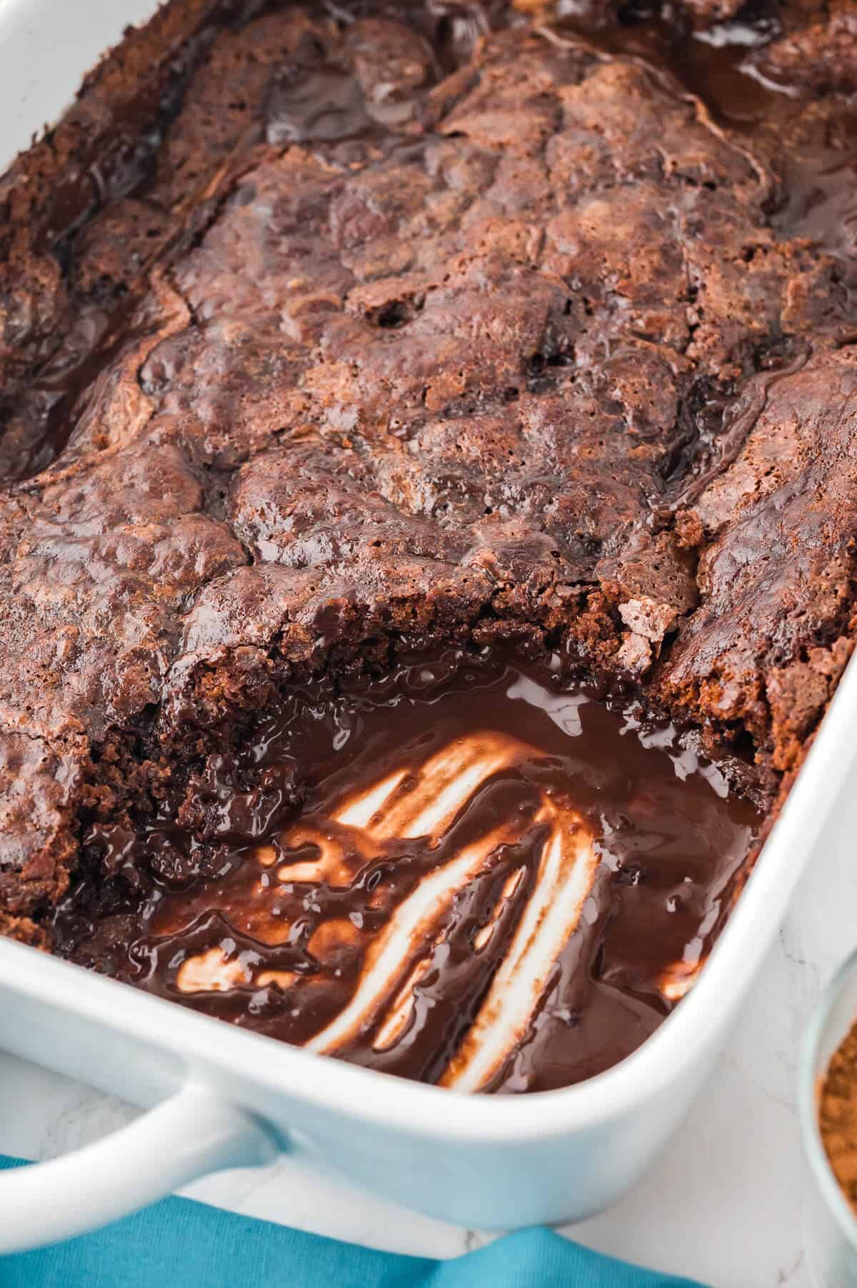 Hot Fudge Pudding Cake in a pan with a piece cut out.