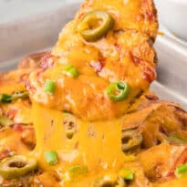 A potato nacho being lifted off a pan.