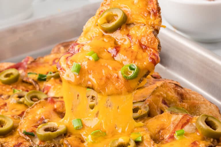 A potato nacho being lifted off a pan.
