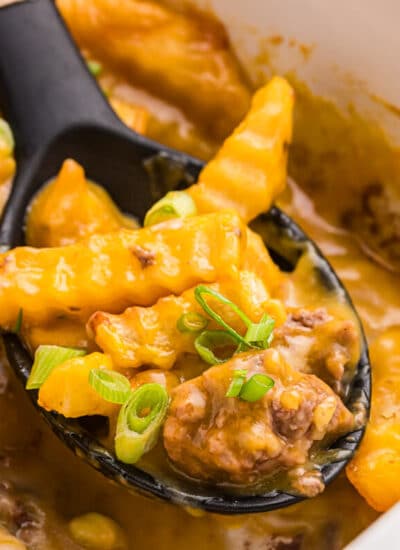French fry Casserole in a pan with a serving spoon.