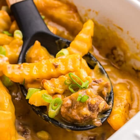 French fry Casserole in a pan with a serving spoon.