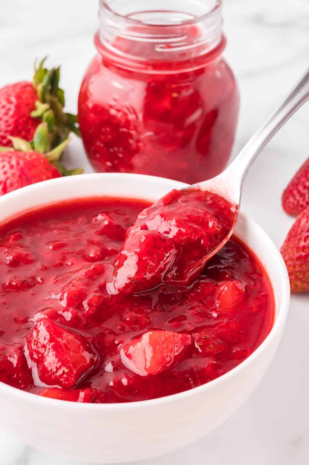 Strawberry sauce in a bowl with a spoon.