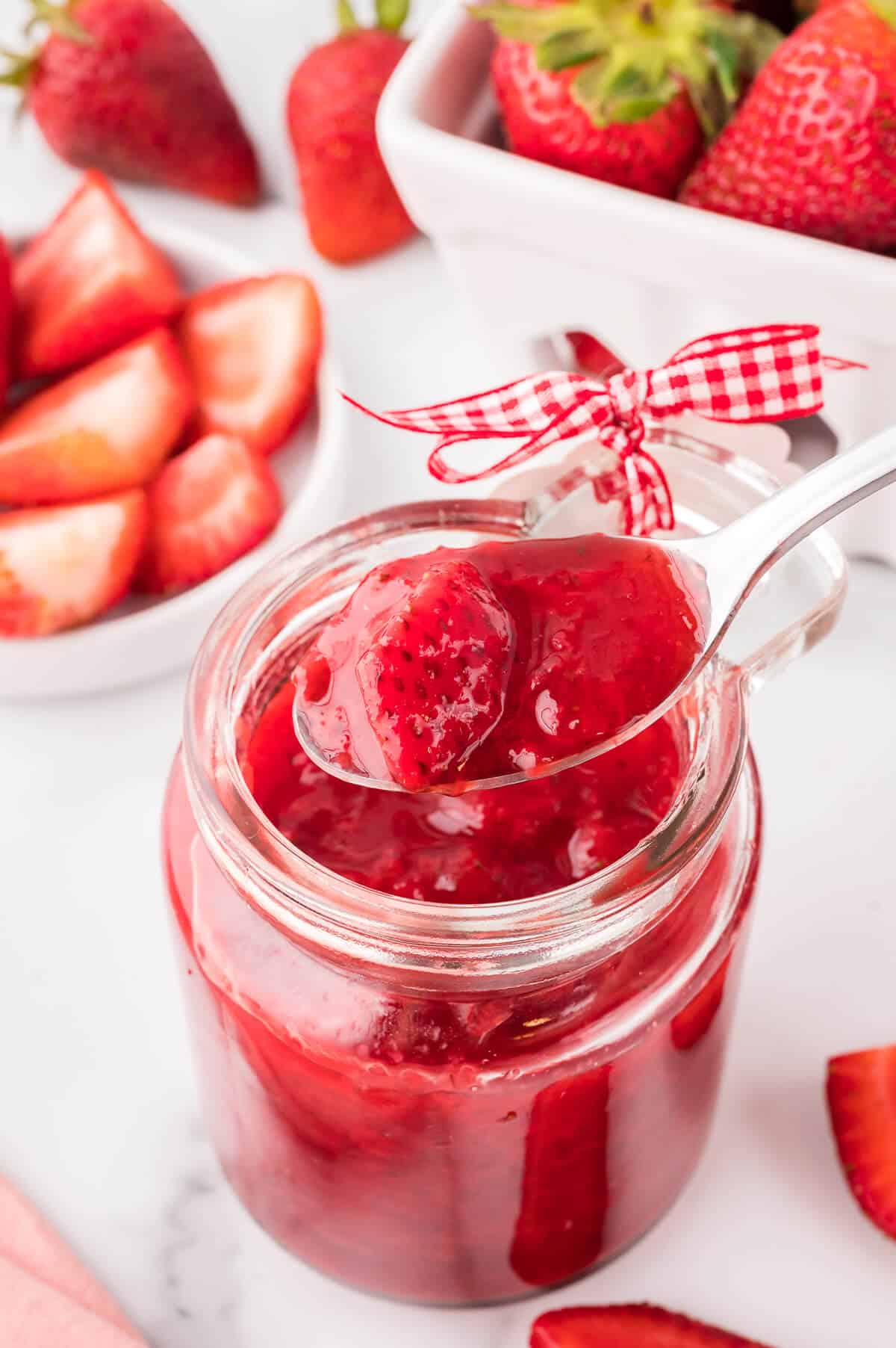 Strawberry sauce in a jar with a spoon.