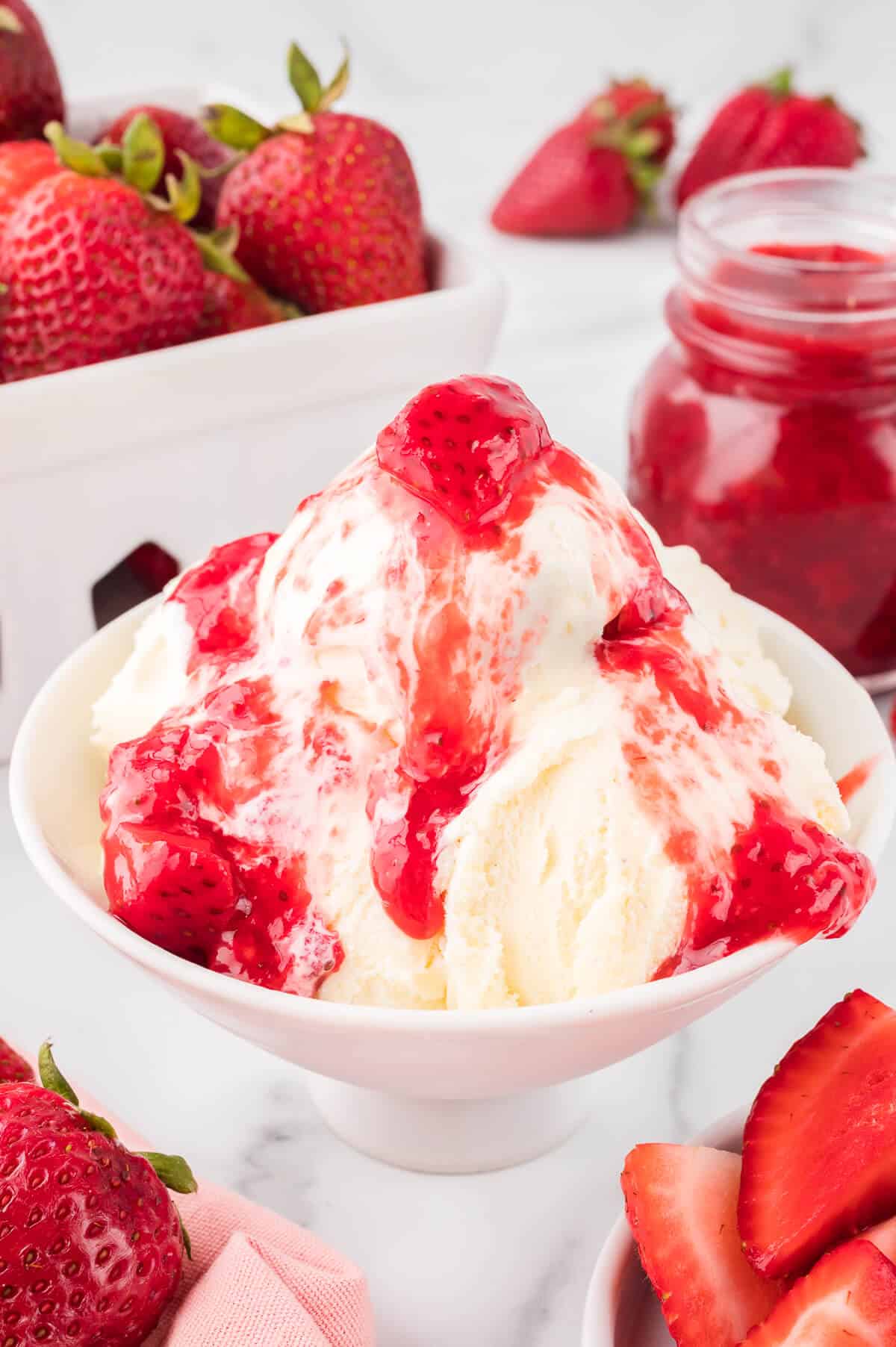 Strawberry sauce on top of vanilla ice cream in a bowl.