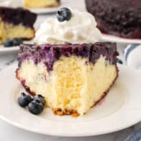 A slice of blueberry upside down cake on a plate with a bite off the end.