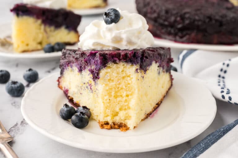 A slice of blueberry upside down cake on a plate with a bite off the end.