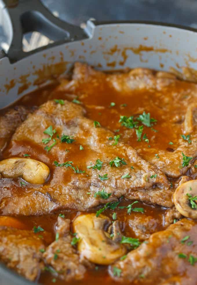 Mushroom Swiss Steak - Tender steak, mushrooms and onions are enveloped in a sweet and savory gravy. This easy dinner recipe pairs nicely with mashed potatoes to sop up all the delicious gravy.