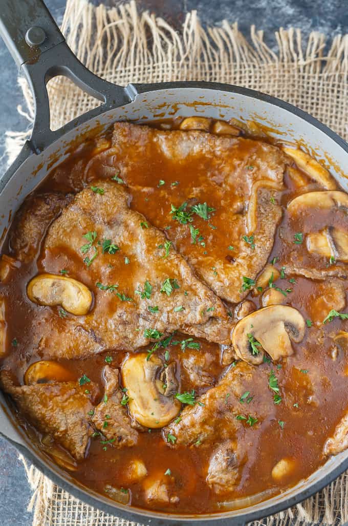 Mushroom Swiss Steak - Tender steak, mushrooms and onions are enveloped in a sweet and savory gravy. This easy dinner recipe pairs nicely with mashed potatoes to sop up all the delicious gravy.