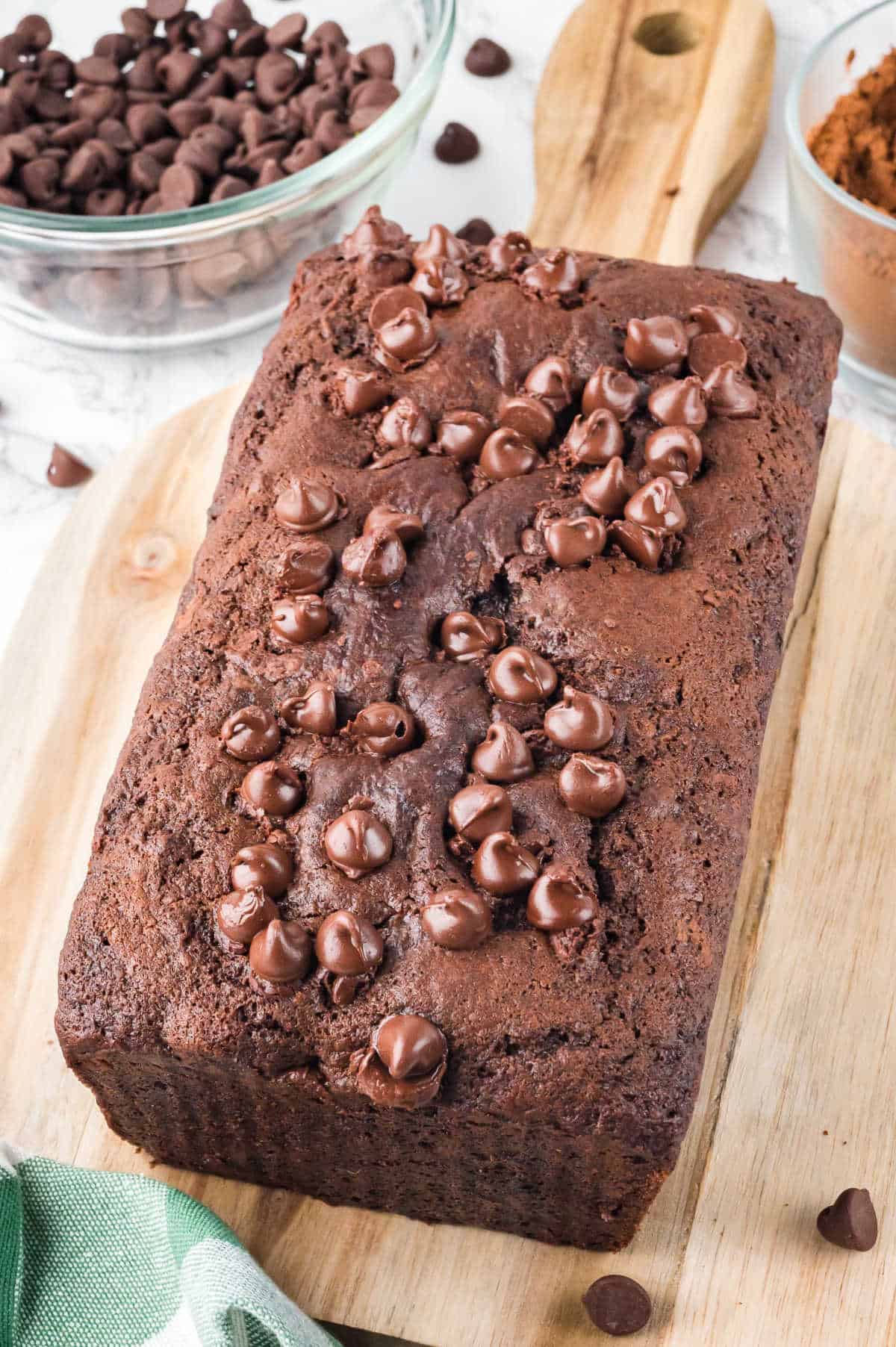 A chocolate zucchini bread loaf on a wooden cutting board.