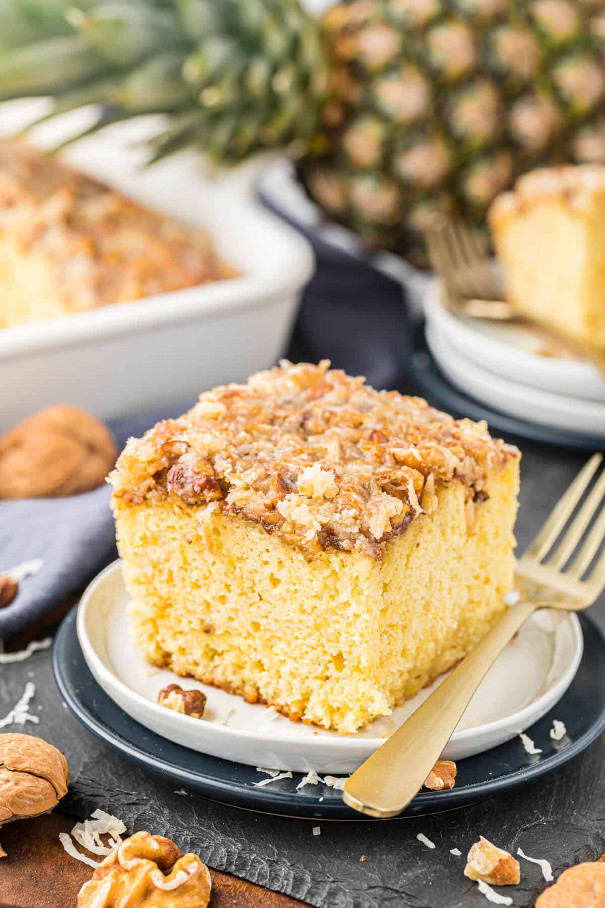 A piece of pineapple cake on a plate with a fork.