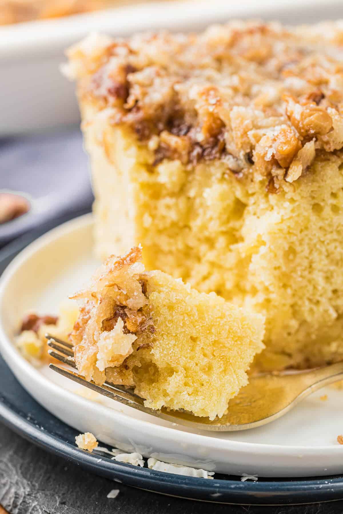 A piece of pineapple cake a plate with a bite out of it.