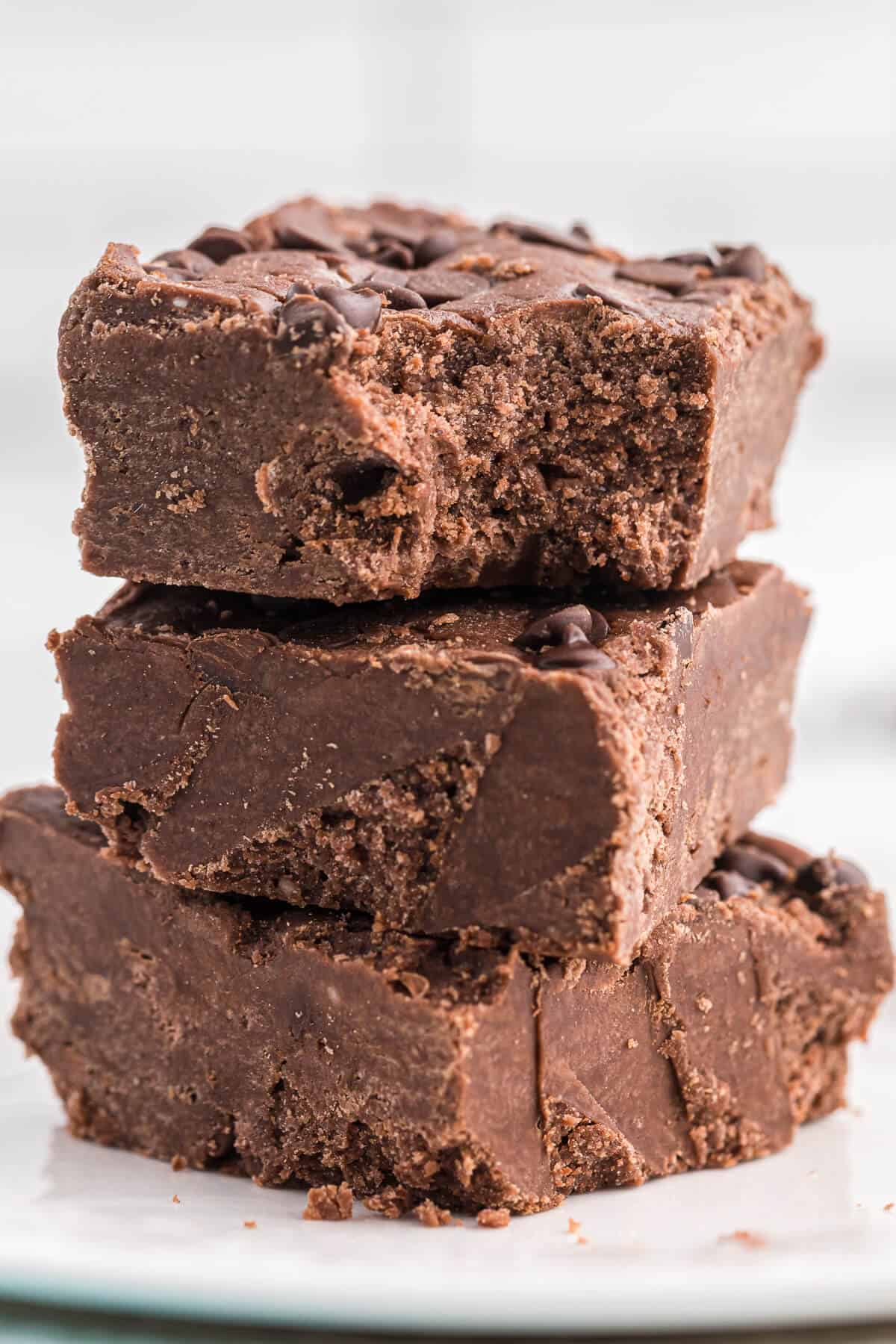 a stack of chocolate cake batter fudge with the top piece having a bite out of it.