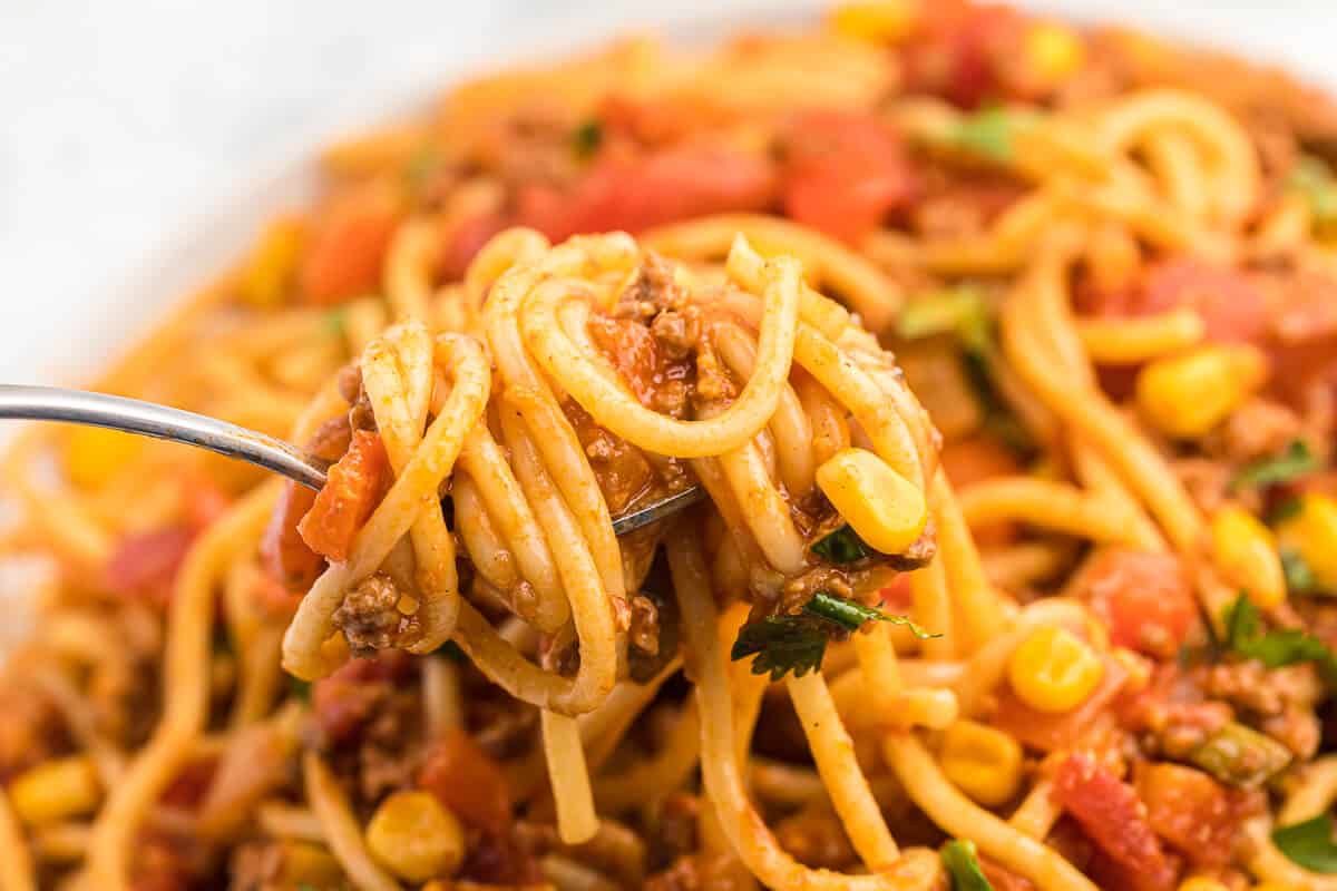 Mexican Spaghetti Recipe - This easy taco pasta recipe is filled with cheesy ground beef, taco seasoning, peppers, corn, tomatoes and noodles. It's simple to make with just the right amount of spice. The perfect family dinner recipe.