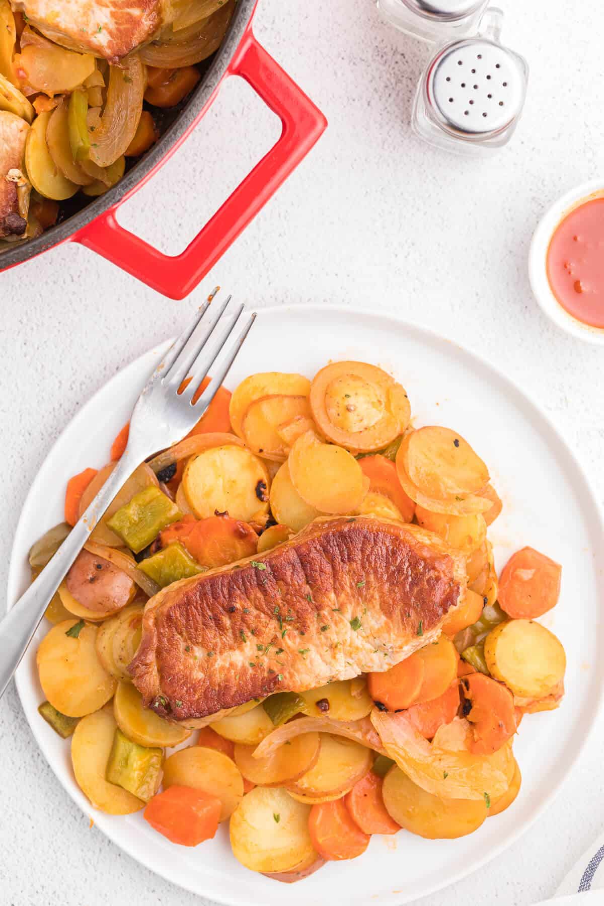 Pork Chop Skillet Dinner Recipe - A simple and delicious one-pan meal! Pork chops are cooked to perfection with potatoes, carrots, onions and green pepper in a tomato sauce with a kick.