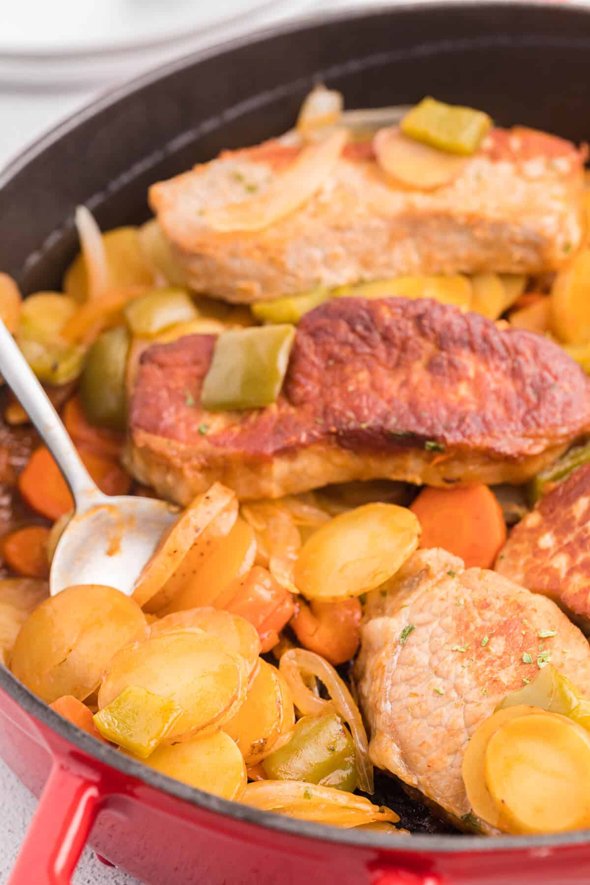 Pork Chop Skillet Dinner Recipe - A simple and delicious one-pan meal! Pork chops are cooked to perfection with potatoes, carrots, onions and green pepper in a tomato sauce with a kick.