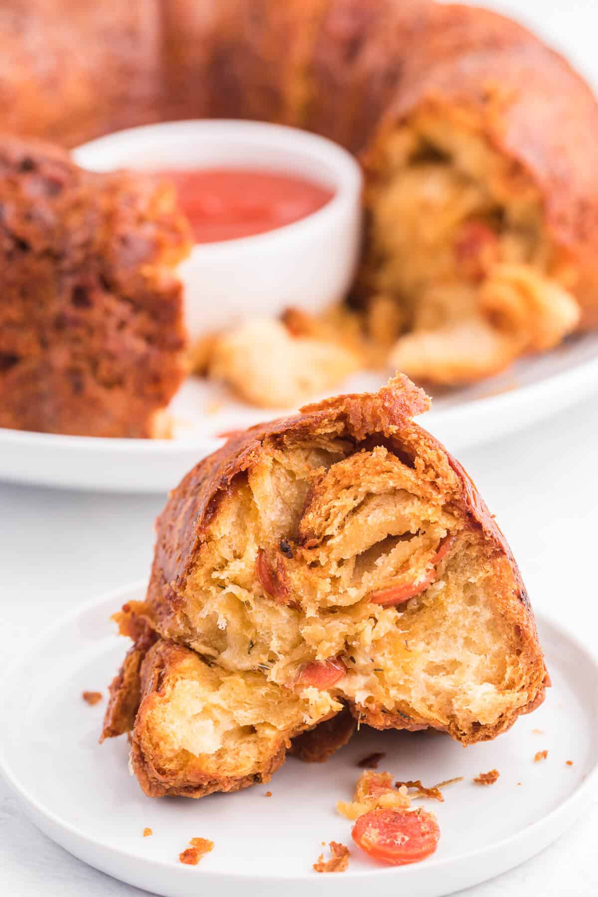 Pizza Monkey Bread Recipe - This pull apart game day recipe is simple to make in a bundt pan. Crescent roll dough, pepperoni and mozzarella cheese are combined to make the most delicious Italian-style appetizer. Serve with some pizza sauce for easy dipping!