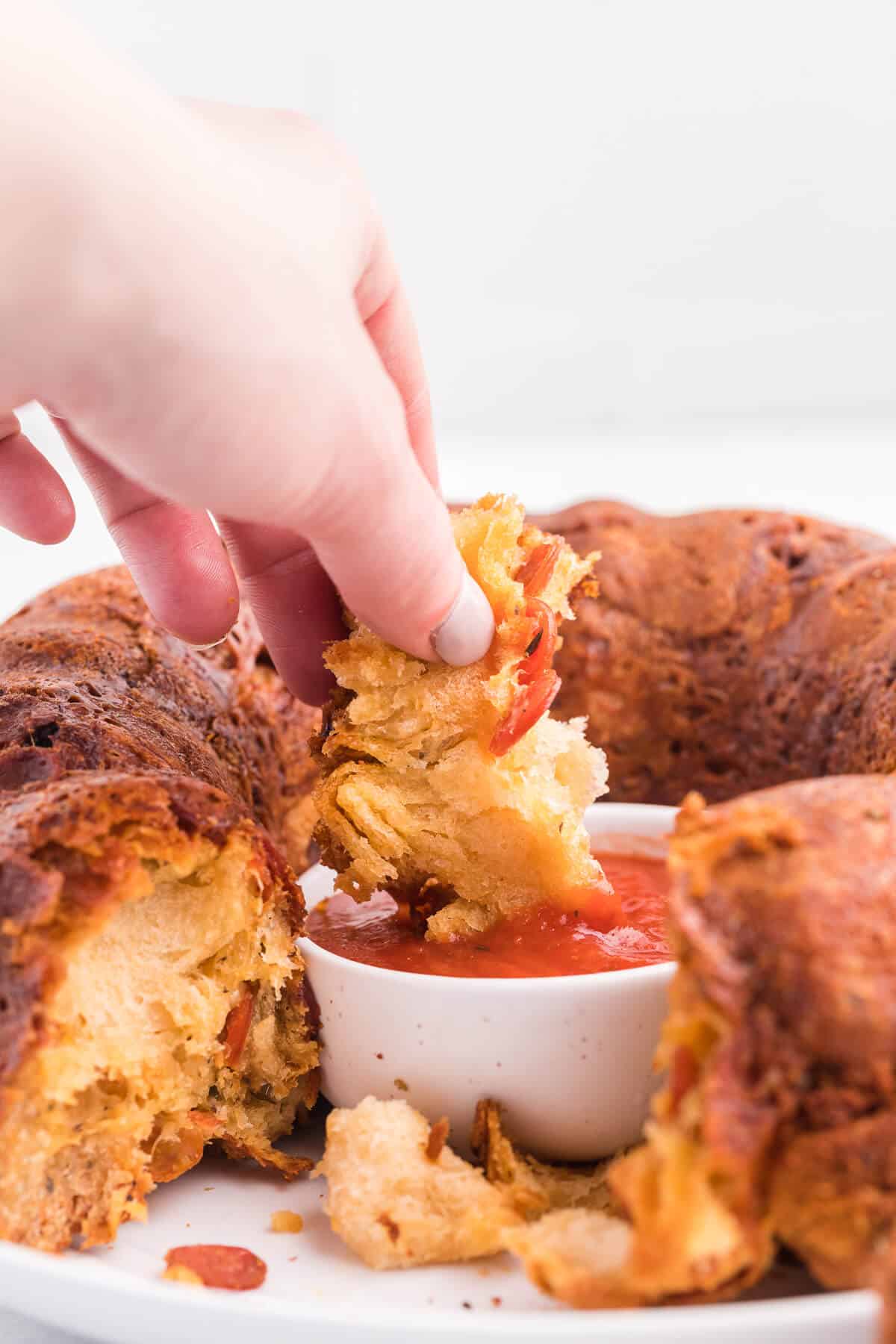 Pizza Monkey Bread Recipe - This pull apart game day recipe is simple to make in a bundt pan. Crescent roll dough, pepperoni and mozzarella cheese are combined to make the most delicious Italian-style appetizer. Serve with some pizza sauce for easy dipping!